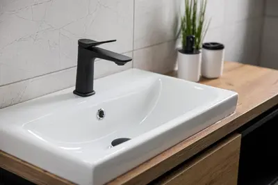 a white bathroom sink with a black faucet at Noclegi Sunny House in Witanowice