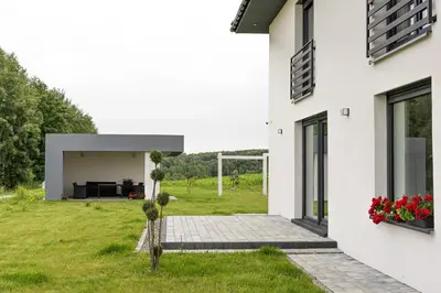 a white house with a garden and a patio at Noclegi Sunny House in Witanowice