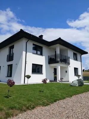 a white house with a black roof at Noclegi Sunny House in Witanowice
