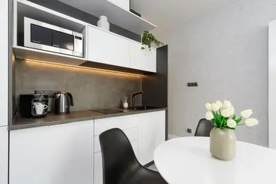 a white kitchen with a table and black chairs at Old Town Apartment with Balcony - Rajska 3 Street in Kraków