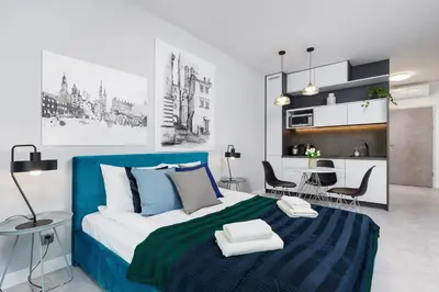 a bedroom with a blue and white bed and a kitchen at Old Town Apartment with Balcony - Rajska 3 Street in Kraków