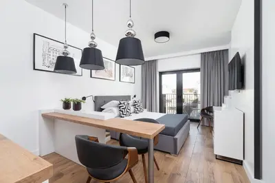 a kitchen and living room with a dining table and a bed at Cozy studio with a balcony - Rajska 3 street in Kraków