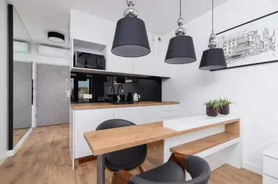 a kitchen with a wooden table and black chairs at Cozy studio with a balcony - Rajska 3 street in Kraków