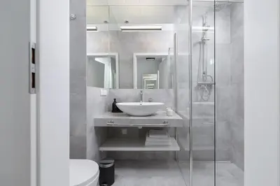 a bathroom with a sink and a glass shower at Cozy studio with a balcony - Rajska 3 street in Kraków