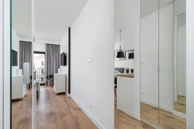 a living room with white walls and wooden floors at Cozy studio with a balcony - Rajska 3 street in Kraków