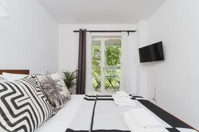 a white bedroom with a bed and a television at 3-Bedroom Apartment with balcony- Krowoderska in Kraków