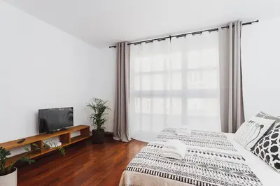a white bedroom with a bed and a television at 3-Bedroom Apartment with balcony- Krowoderska in Kraków