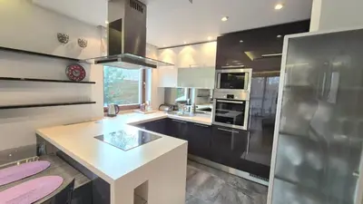 a kitchen with black cabinets and a white counter top at Apartament Zielony Z Ogrodem in Kraków