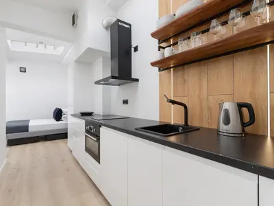 a kitchen with white cabinets and a black counter top at Apartment in Kazimierz District - Starowislna 43 in Kraków