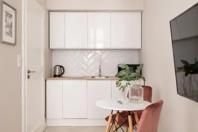 a kitchen with white cabinets and a table at Studio for two - Kazimierz- 43 Starowiślna Street in Kraków