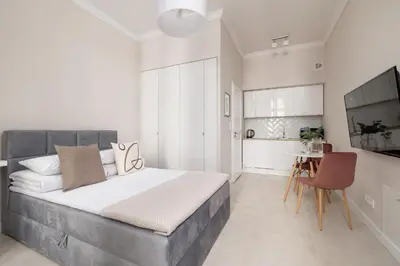 a bedroom with a large bed and a kitchen at Studio for two - Kazimierz- 43 Starowiślna Street in Kraków