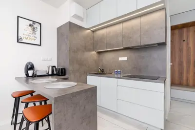 a kitchen with white cabinets and a counter with stools at Modern Apartment Old Town Cracow by Noclegi Renters in Kraków