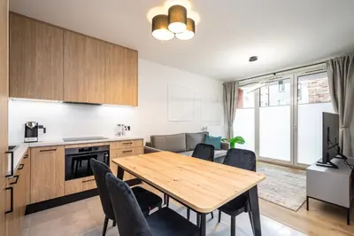 a kitchen and dining room with a wooden table and chairs at Apollo Apartments Prochowa 6 in Kraków