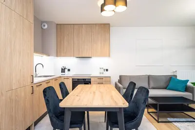 a kitchen and dining room with a wooden table and chairs at Apollo Apartments Prochowa 6 in Kraków