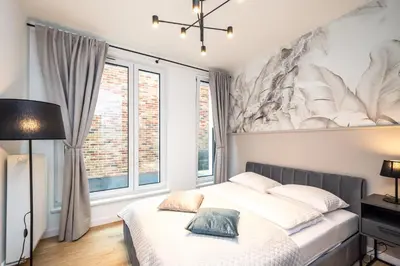 a bedroom with a bed and a large window at Apollo Apartments Prochowa 6 in Kraków