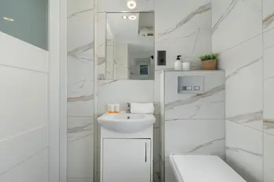 a white bathroom with a sink and a mirror at Central Kraków Apartment by Noclegi Renters in Kraków