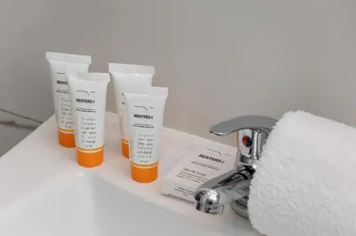 a row of bottles of sunscreen sitting on a bathroom sink at Central Kraków Apartment by Noclegi Renters in Kraków