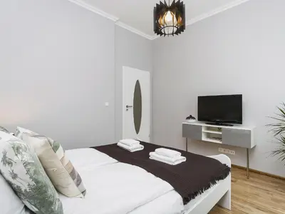a white bedroom with a bed and a tv at Two Bedroom Apartment - Rzeszowska 4 in Kraków