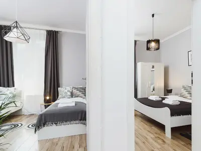 a white bedroom with a bed and a mirror at Two Bedroom Apartment - Rzeszowska 4 in Kraków