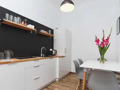 a kitchen with white cabinets and a table with pink flowers at Two Bedroom Apartment - Rzeszowska 4 in Kraków