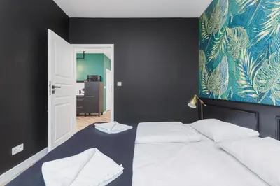 a bedroom with a white bed with a blue wall at Podgórze Golden Oriole Apartment Cracow by Renters Prestige in Kraków