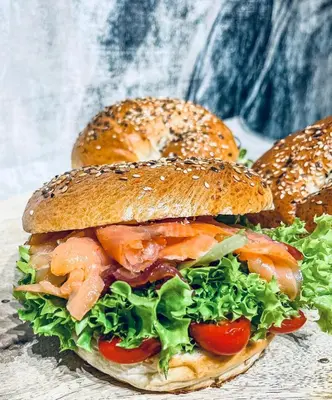 a sandwich with lettuce and tomatoes on a bagel at Rooftop Wawel view with jacuzzi l luxury apartment in Kraków