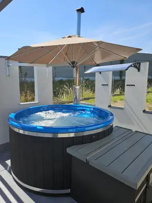 a hot tub with an umbrella on a deck at TinyApartament in Skawa
