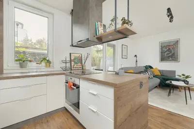 a kitchen with white cabinets and a living room at Zbożowa 2A Apartments Nowy Kleparz Cracow by Noclegi Renters in Kraków