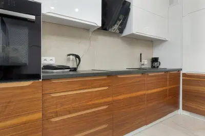 a kitchen with wooden cabinets and a microwave at Zbożowa 2A Apartments Nowy Kleparz Cracow by Noclegi Renters in Kraków