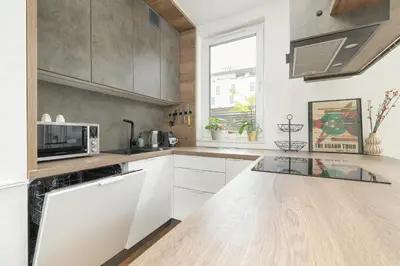 a kitchen with white cabinets and a counter top at Zbożowa 2A Apartments Nowy Kleparz Cracow by Noclegi Renters in Kraków