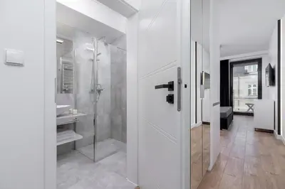 a white bathroom with a shower and a sink at City center studio with a balcony - Rajska 3 in Kraków