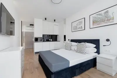 a white bedroom with a large bed and a kitchen at City center studio with a balcony - Rajska 3 in Kraków