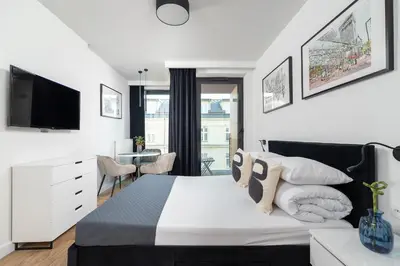 a white bedroom with a bed and a tv at Studio for two with a balcony - Rajska 3 street in Kraków