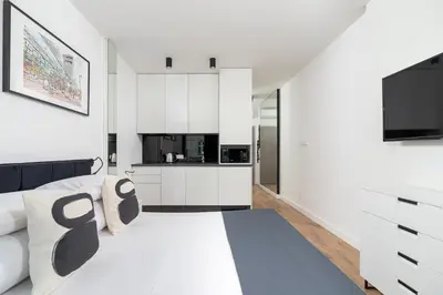 a white bedroom with a large bed and a tv at Studio for two with a balcony - Rajska 3 street in Kraków