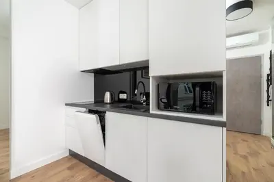 a kitchen with white cabinets and a microwave at Studio for two with a balcony - Rajska 3 street in Kraków
