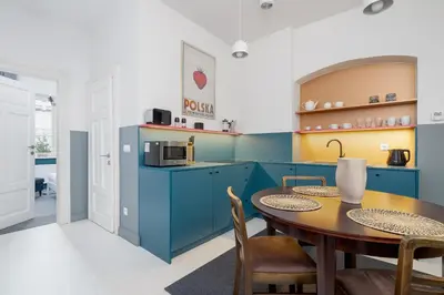 a kitchen with blue cabinets and a table and chairs at Św Jana Street - Main Square Apartment in Kraków