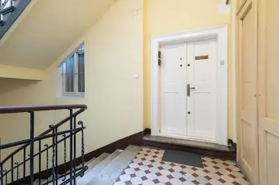 a hallway with a white door and a checkered floor at Św Jana Street - Main Square Apartment in Kraków