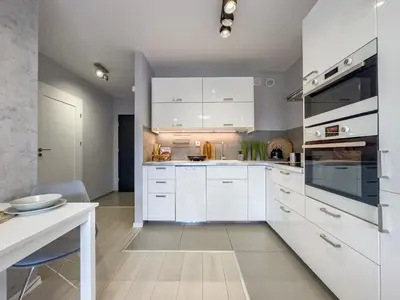 a white kitchen with white cabinets and a table at Nadwiślańska Przystań Apartament z widokiem na Wisłę in Kraków