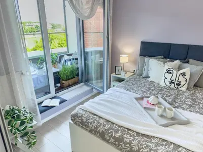a bedroom with a bed with a tray with a book at Nadwiślańska Przystań Apartament z widokiem na Wisłę in Kraków