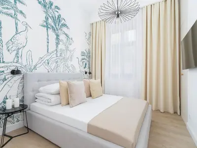 a white bedroom with a bed with a chandelier at 4 Bedroom Apartment - Main Square in Kraków