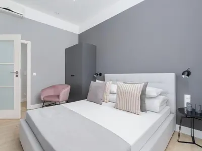 a bedroom with a white bed and a pink chair at 4 Bedroom Apartment - Main Square in Kraków