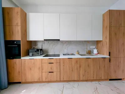 a kitchen with wooden cabinets and a white counter top at Dębowa 4 by Homeprime in Kraków