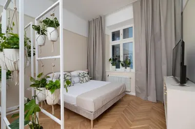 a white bedroom with a bed and plants at 2 - bedroom apartment - Rejtana 10 in Kraków