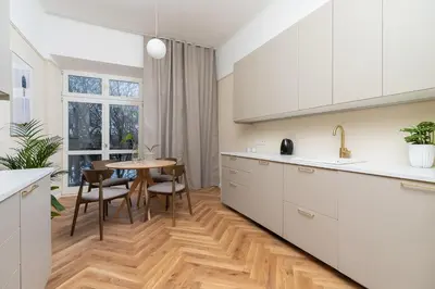 a kitchen with white cabinets and a table with chairs at 2 - bedroom apartment - Rejtana 10 in Kraków
