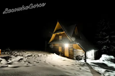 a house in the snow with a light on it at Prawdziwy domek w górach in Nowy Targ