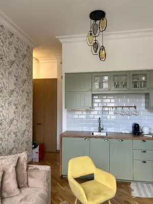 a kitchen with green cabinets and a yellow chair at Vintage Kalwaryjska Apartment in Kraków