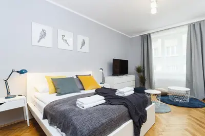 a white bedroom with a bed and a tv at Two Bedroom Apartment - Rzeszowska 8 Street in Kraków