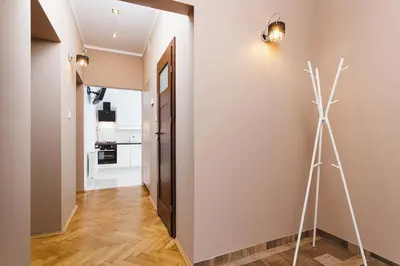 a hallway with a white wall and a tripod next to a door at Two Bedroom Apartment - Rzeszowska 8 Street in Kraków