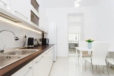 a white kitchen with a sink and a table at Two Bedroom Apartment - Rzeszowska 8 Street in Kraków