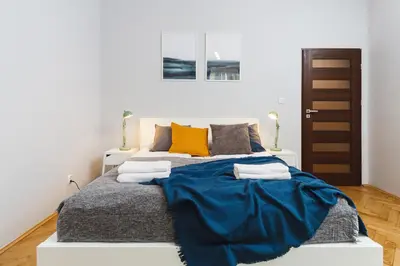 a bedroom with a bed with a blue blanket on it at Two Bedroom Apartment - Rzeszowska 8 Street in Kraków